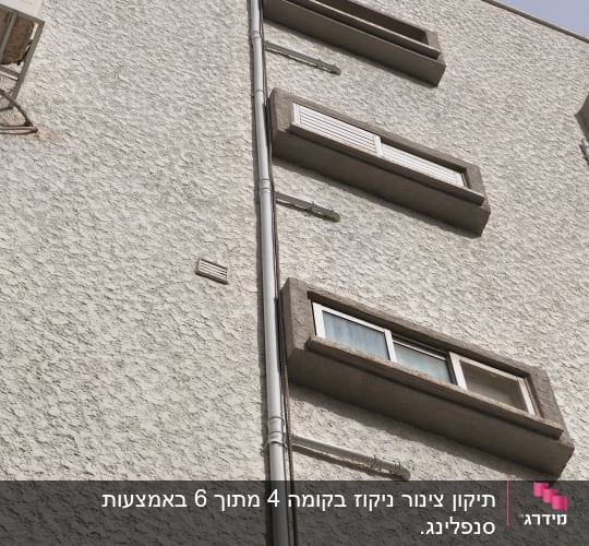 צינור חיצוני על קיר בניין עם חלונות